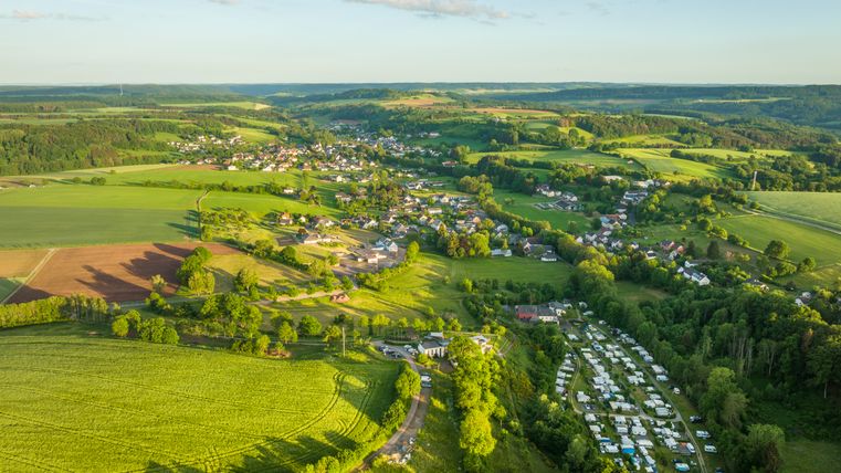 Vue aérienne d'un paysage verdoyant avec des champs, un village et un camping.