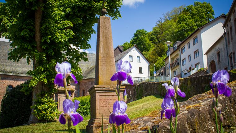 Des fleurs devant un obélisque et des bâtiments à Kyllburg.