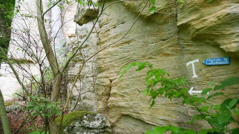 Paroi rocheuse avec panneau indicateur du Teufelsloch (trou du diable) dans la forêt.