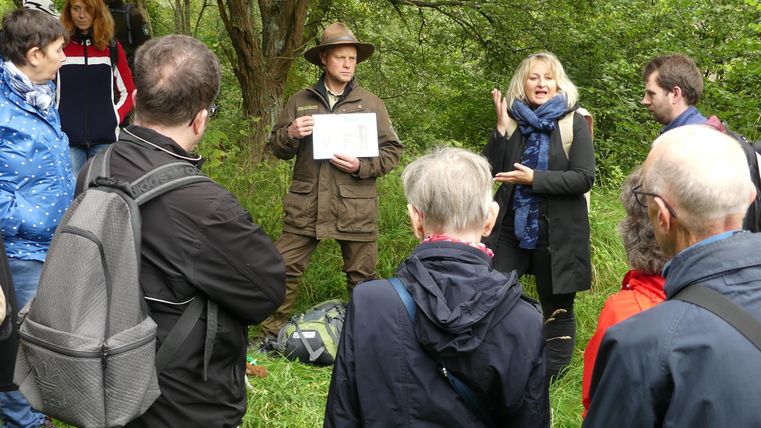 A ranger shows the group something. A sign language interpreter translates.