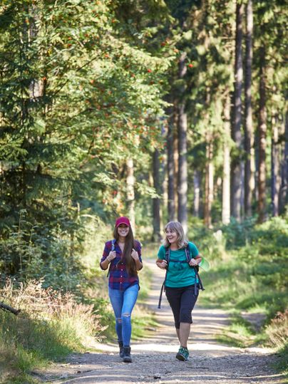 Twee vrouwen lopen over een bospad in de Hocheifel.
