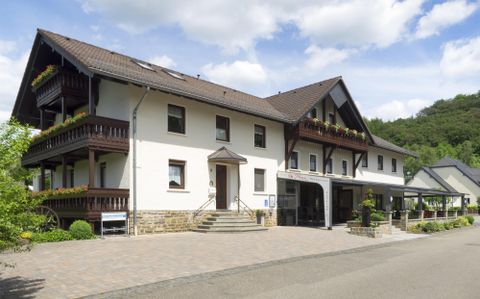 A modern building with multiple floors and balconies. Surrounded by trees and a clear sky.