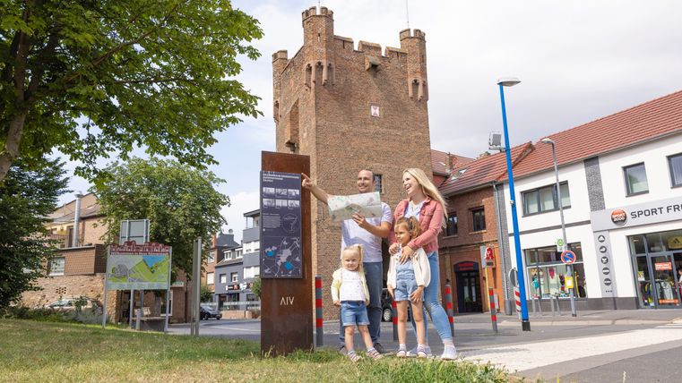 A family stands in front of Zülpich Castle with a map in their hands.