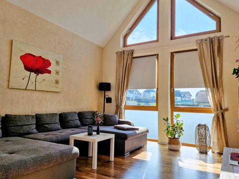 A bright living room with large windows and a beautiful view. A cozy sofa and a plant complement the space.