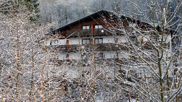 Ein chaletähnliches Gebäude in einer verschneiten Landschaft. Die Bäume sind mit frischem Schnee bedeckt.