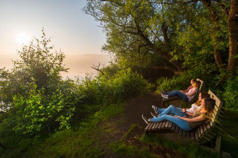 Je zwei Personen auf zwei Traumliegen beim Anschauen des Sonnenuntergangs am See