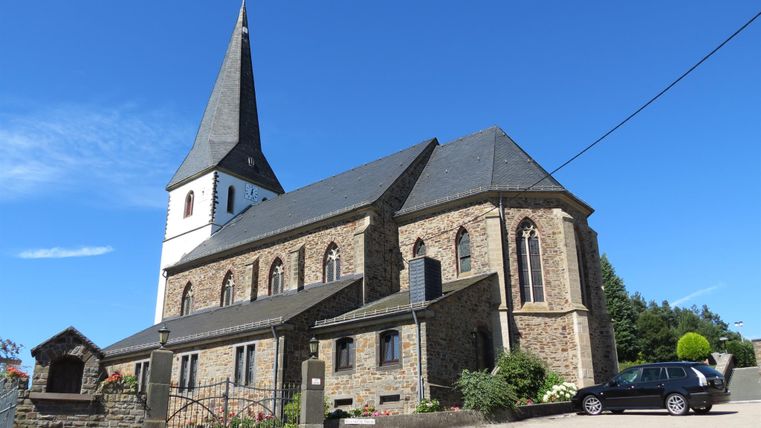 Église paroissiale de Reifferscheid avec une tour pointue et un ciel bleu.
