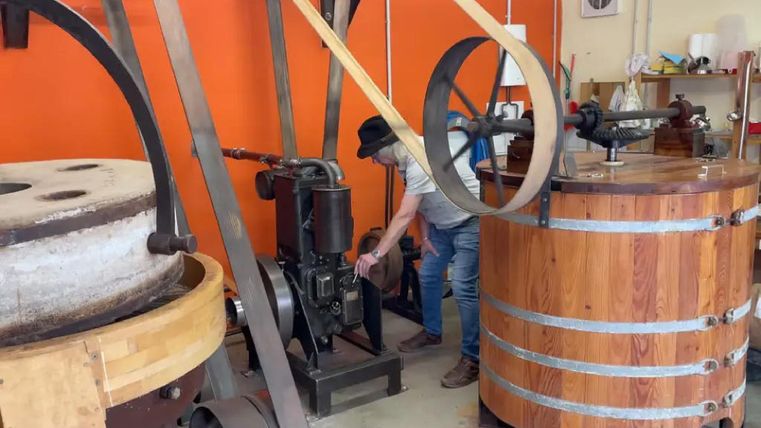 Man with a hat indicates something on a device - is surrounded by mills
