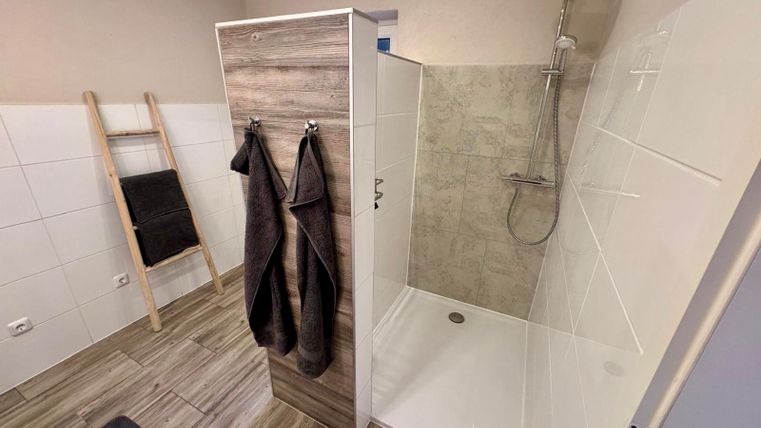 A spacious and modern bathroom with natural light, a walk-in shower, a large sink, a toilet and storage space.