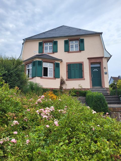 Charmantes, historisches Haus mit grünen Fensterläden in Hetzerath und idyllischem Vorgarten mit blühenden Rosen.