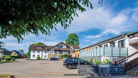 Un bâtiment traditionnel avec un mélange de colombages et de design moderne. Il se trouve le long d'une route et est entouré d'arbres.