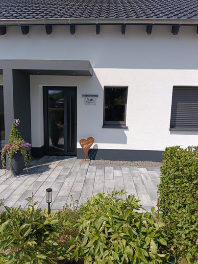 Een modern huis met een elegante voordeur. De voortuin is met planten versierd en heeft een geplaveide pad.