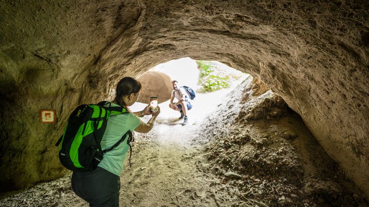 Een persoon neemt met een smartphone een foto van een andere persoon in een grot.