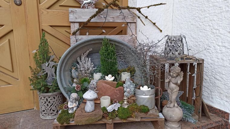 Een decoratieve entree met planten, stenen en verschillende kunstenaarsvazen. Alles is in natuurlijke aardetinten gehouden en straalt een gezellige sfeer uit.