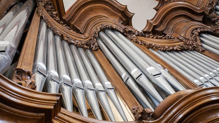 An artistic organ with a wood decoration and silver pipes. The details in the construction showcase craftsmanship.