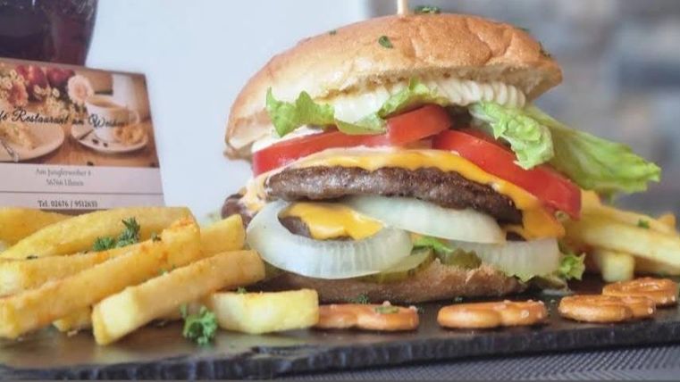 Een sappige burger met kaas, sla, tomaat en uien. Daarbij krokante friet en een drankje.