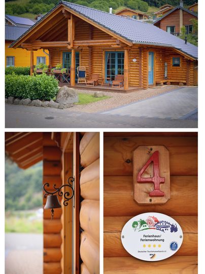 A cozy wooden house with a blue roof, surrounded by green nature. The front door displays a numbered plaque with the number 4.