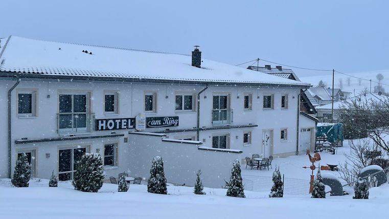 Ein Hotel in einer verschneiten Landschaft. Der Himmel ist grau und die Umgebung ist ruhig und winterlich.