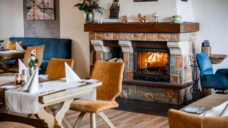 An inviting restaurant with a cozy fireplace. The tables are beautifully set and the decor is modern and stylish.