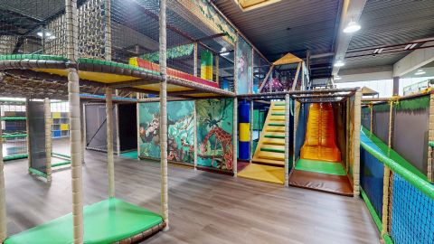 Een grote speeltuin met verschillende glijbanen en klimelementen. De kleurrijke gebieden nodigen kinderen uit om te spelen en te ontdekken.