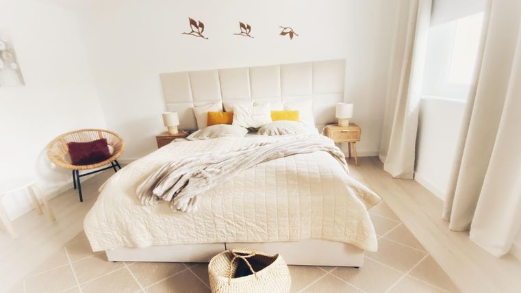 Une chambre lumineuse avec un lit confortable et une décoration chaleureuse. Les murs sont blancs et il y a quelques éléments décoratifs qui créent une atmosphère accueillante.