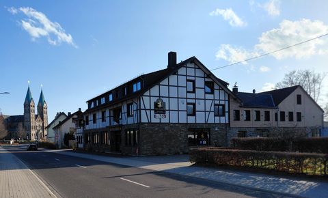 Une charmante maison à colombages avec un café de rue. En arrière-plan, deux flèches d'église sont visibles.