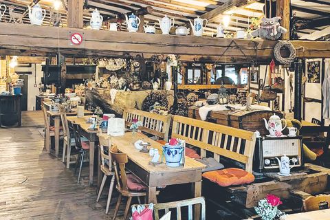 Interieur van het restaurant met houten tafels en stoelen versierd met oude theepotten en -kopjes