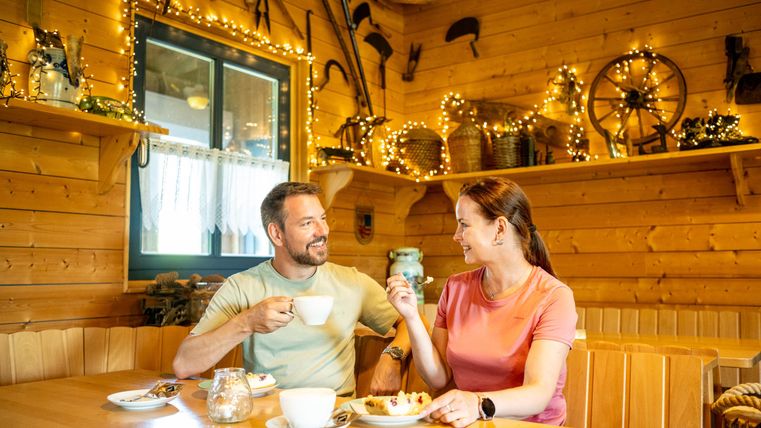 Ein gemütliches Café mit rustikaler Holzdekoration. Ein Paar genießt gemeinsam Kaffee und Kuchen.