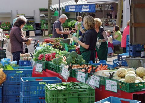 Colorful market hustle on a summer day with buyers and vendors at a vegetable stall