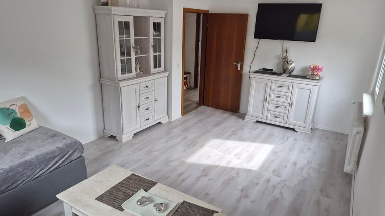 Een lichte woonkamer met moderne meubels in het wit. De ruimte heeft een prettige sfeer en veel daglicht.