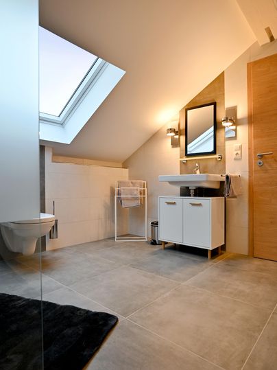 Ein modernes Badezimmer mit einer großen Fensterfläche und einem hellen Holzdekor. Es verfügt über eine stilvolle Waschbeckenunterschrank und eine separate Toilette.