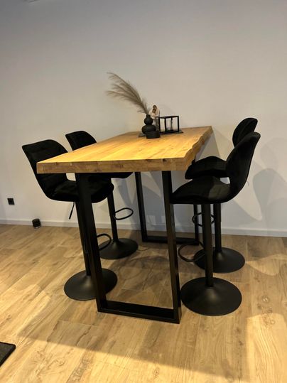 An elegant wooden table with four black high chairs.
