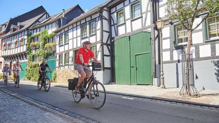 Radfahrer in historischer Straße mit Fachwerkhäusern in Kommern.