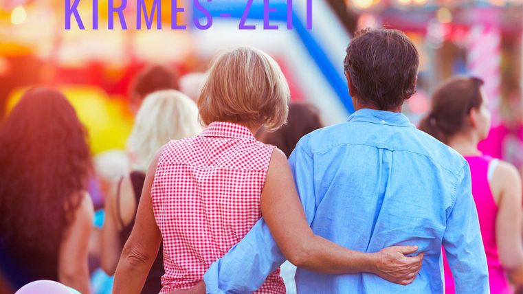A couple walks hand in hand through the fair. Colorful lights and a festive atmosphere surround them.