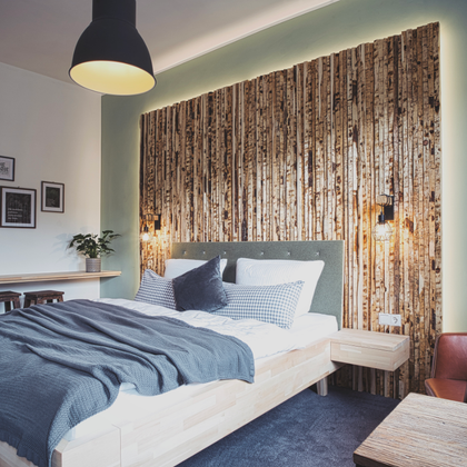 Une chambre moderne avec un lit confortable et un revêtement en bois sur le mur. L'aménagement est minimaliste et élégant, avec un éclairage chaleureux.
