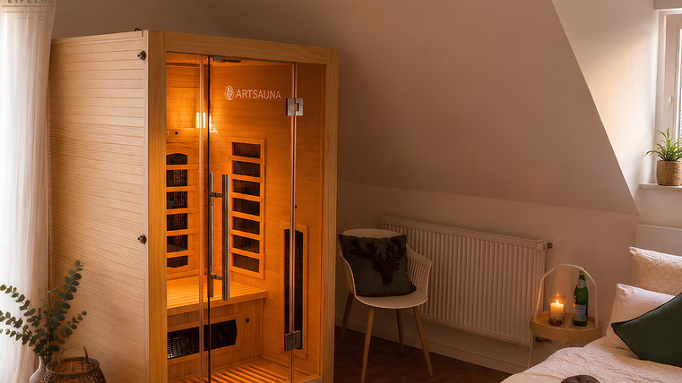 Eine moderne Infrarotsauna in einem stilvoll eingerichteten Raum. Der Raum ist gemütlich mit einer Sessel, Pflanzen und sanfter Beleuchtung gestaltet.