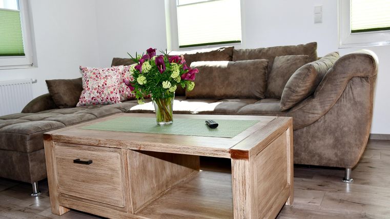 A cozy living room with a brown sofa and a wooden table.
On the table, there is a bouquet of flowers in a vase.
