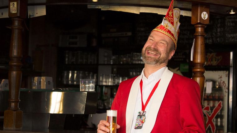 Lachender Herr Weininger mit einem Glas Kölsch in der Hand