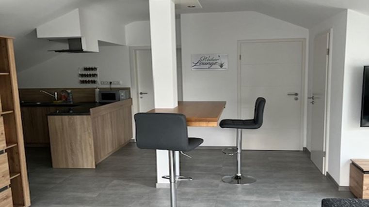 Une cuisine moderne avec un coin repas et des tabourets de bar. L'espace a des murs clairs et un caractère ouvert et accueillant.
