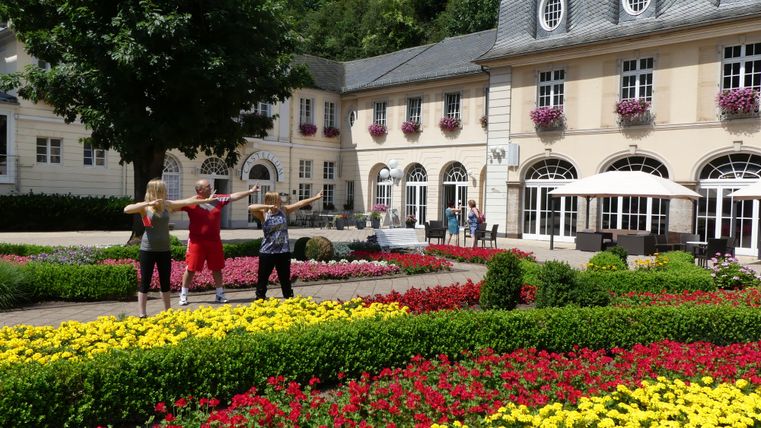 Ein schmaler Weg zwischen moosbedeckten Felsen und üppigem Grün. Der Handlauf führt sicher durch die natürliche Landschaft.