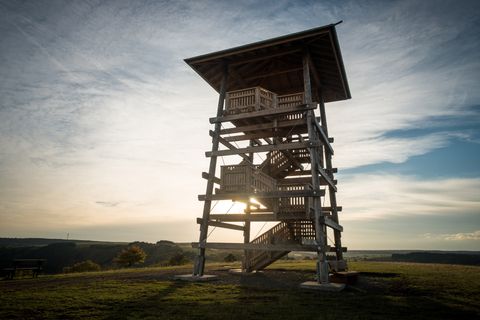 Holzaussichtsturm bei Sonnenuntergang mit weitem Blick über die Landschaft.