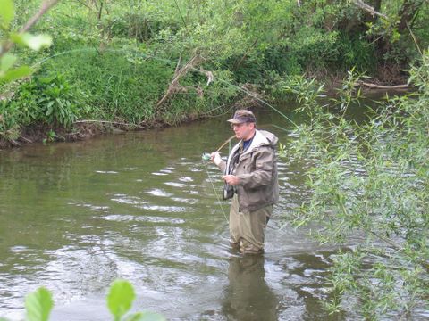Man stands in the Kyll with a fishing rod in hand