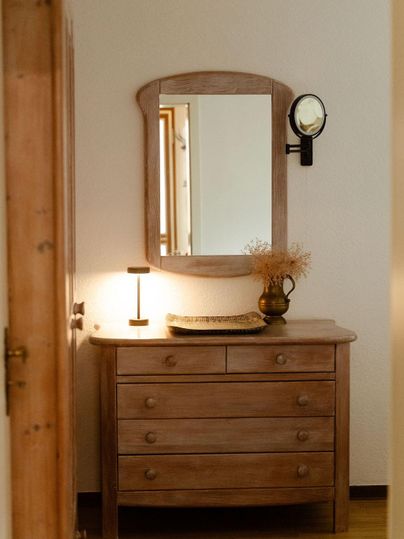 Commode en bois et un miroir dans la chambre. Une lumière douce éclaire la pièce et crée une atmosphère accueillante.