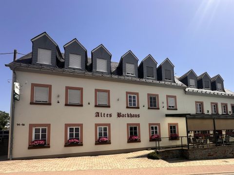 Een historisch gebouw met de naam "Altes Brauhaus". De façade is licht en heeft meerdere ramen en bloembakken.