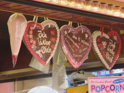 Decorated gingerbread hearts hang at a sales booth. Some hearts bear the inscriptions "I love you" and "Do you know how much I love you?"