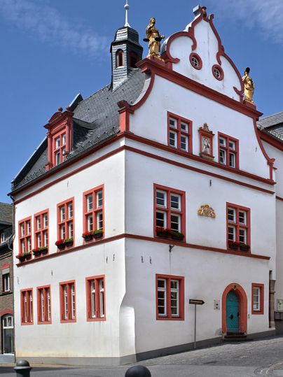 Un bâtiment historique avec une façade blanche et des accents rouges. Il a de nombreuses fenêtres et une structure de toit frappante.