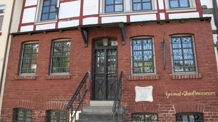 Vakwerkhuis met rode bakstenen gevel en museumbord in Adenau.