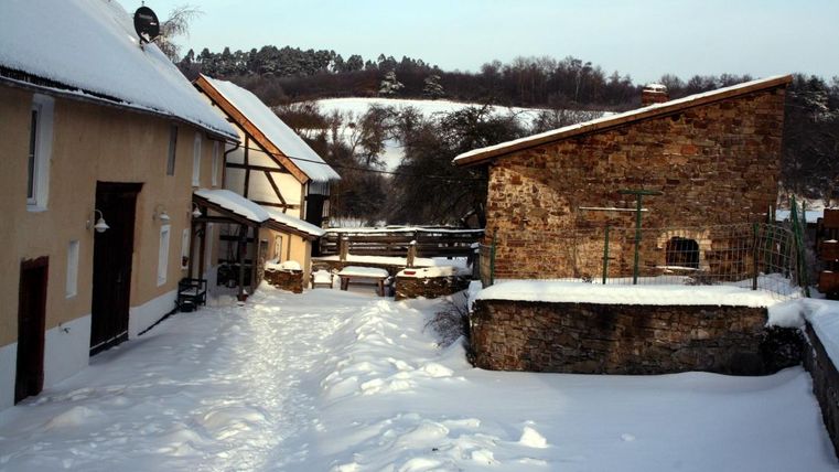 Een winterse binnenplaats met besneeuwde paden. Oude gebouwen van steen en hout omringen het zachte, besneeuwde landschap.