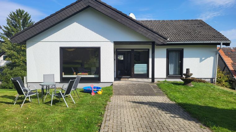 A modern single-family home with a well-kept garden. In front of the door is a seating area with garden furniture.