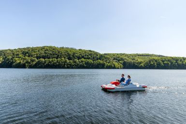 Zwei Personen fahren Tretboot auf dem Rursee